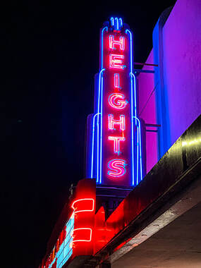 A neon sign displays vivid pink and blues with the word Heights aglow.